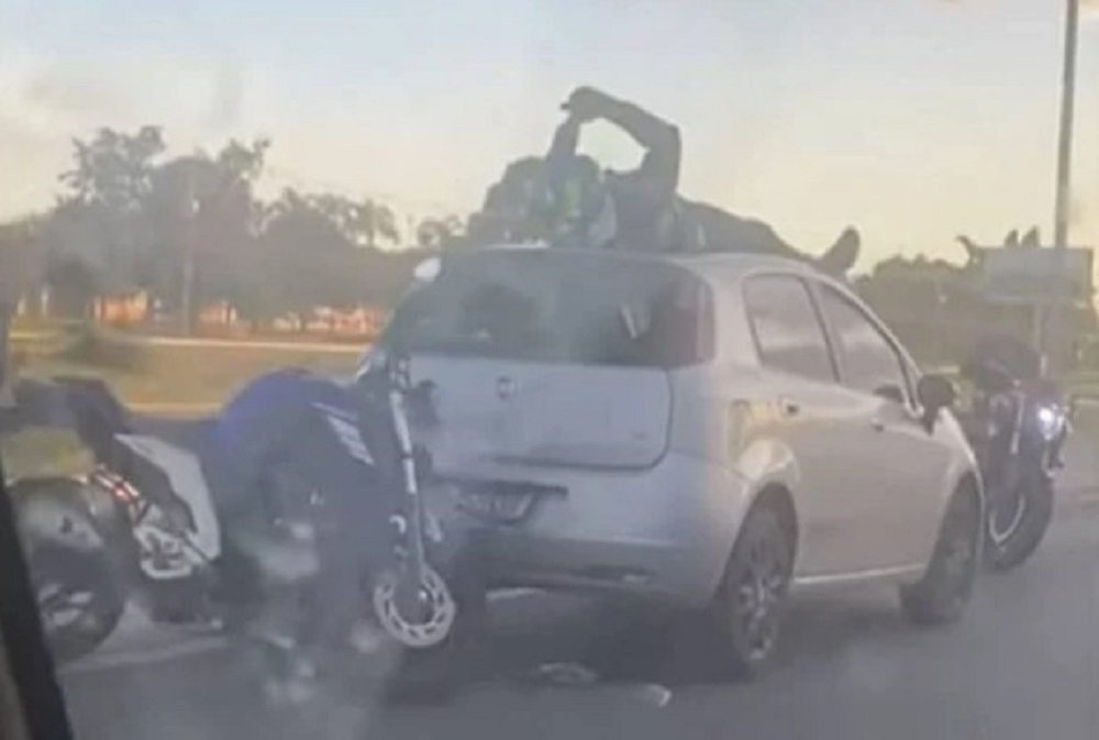 Após bater em traseira de carro motociclista para em cima do veículo; veja vídeo